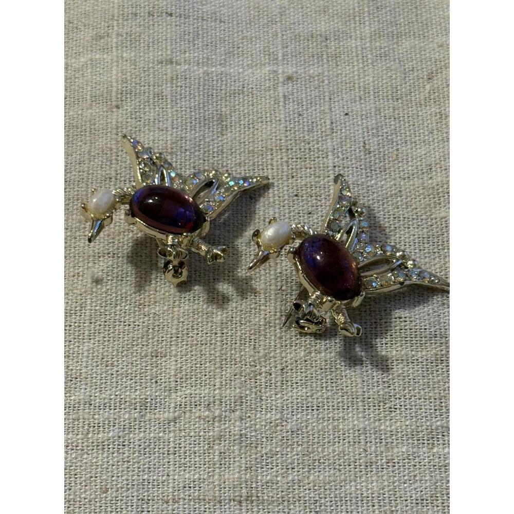 A pair of vintage silver-tone bird brooches with purple stones and rhinestones.